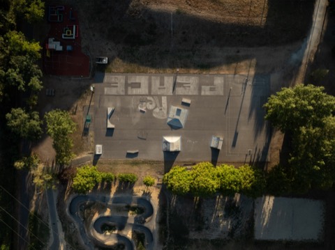 Luftaufnahme des Schwarzen Platzes in Krems: Skate-Obstacles, Rails, Basketballplatz und großes Peace-Zeichen am Boden.