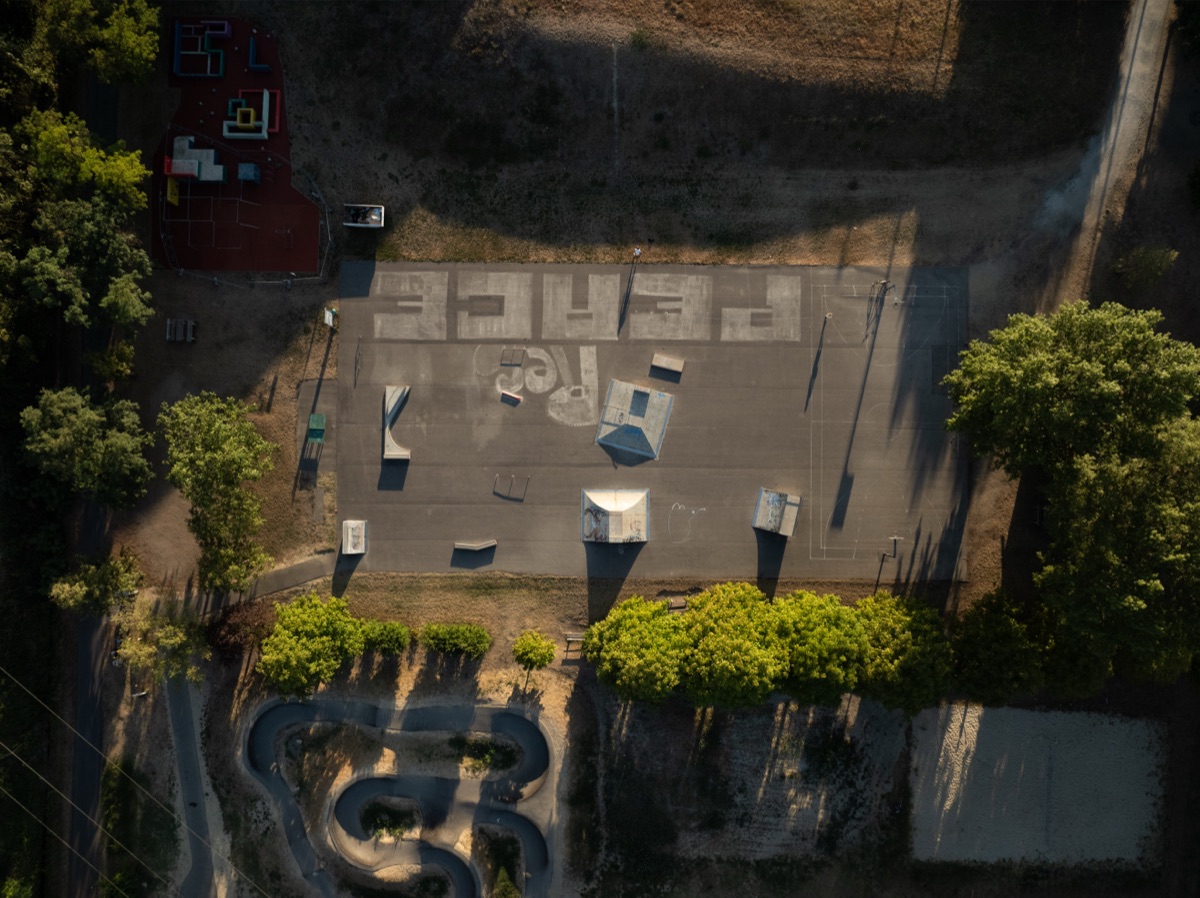 Luftaufnahme des Schwarzen Platzes in Krems: Skate-Obstacles, Rails, Basketballplatz und großes Peace-Zeichen am Boden.