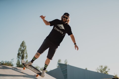 Karl macht einen Turn auf der Pyramide im OG Park, schwarzes Emerica-Shirt, sonniger blauer Himmel.