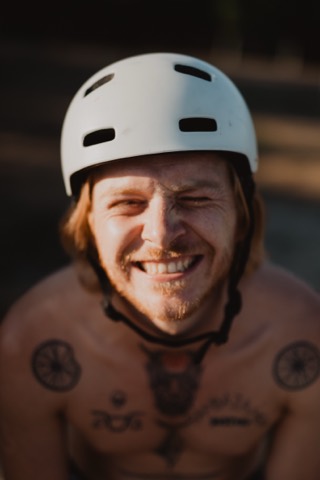 Max Gabriel, Obmann der Black Place Society, lacht in Nahaufnahme mit weißem Helm im warmen Abendlicht am Schwarzen Platz