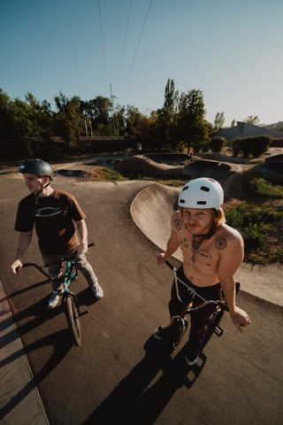 Max und Paul mit ihren BMX-Rädern vor dem Pump Track am Schwarzen Platz, Max blickt in die Kamera.