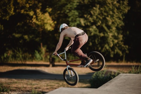 Max Gabriel springt mit dem BMX-Rad über eine Betonrampe am Schwarzen Platz, Bäume im Hintergrund.