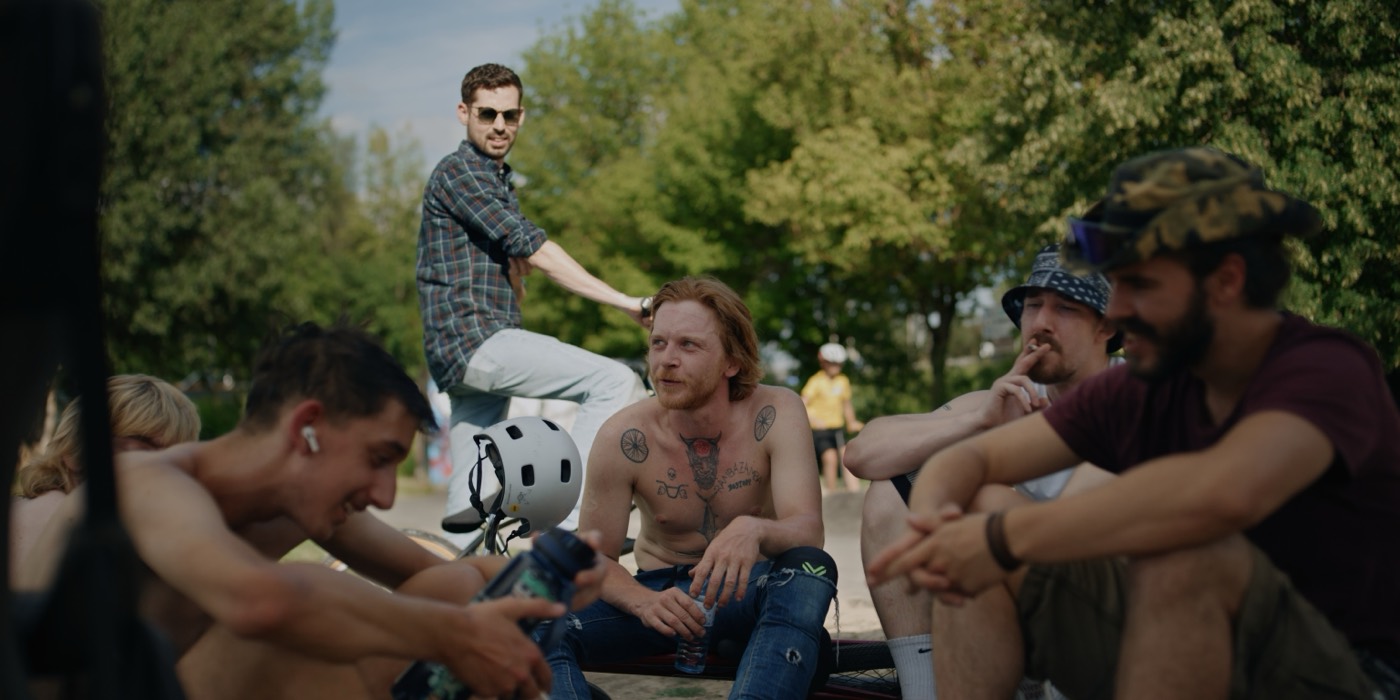 Gruppe von Fahrern, die am Rand des Skateparks sitzt und lacht